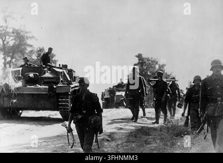 Deutsche Panzertruppen und Infanterie auf dem Marsch an der Ostfront, mit einem StuG III Panzerjäger und einem SdKfz 222 Panzerwagen, 1941-1944. Stockfoto
