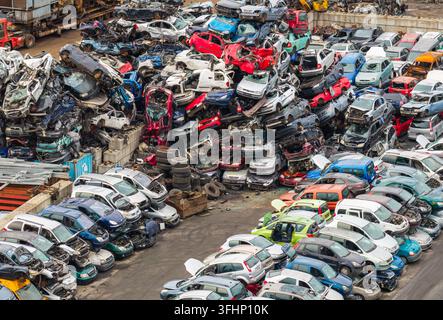 Luftaufnahme eines großen Autoschrottplatzes mit Stapeln von zerkleinerten Fahrzeugen, bunten Karosserien und Metallschrott in einer Recyclinganlage für Altfahrzeuge Stockfoto