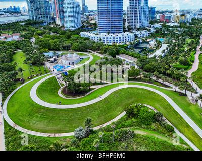 Miami Beach, Vereinigte Staaten - 21. September 2024: Luftaufnahme von South Beach mit einem sich windenden Weg durch üppige grüne Parkanlagen mit modernen Hochhäusern Stockfoto