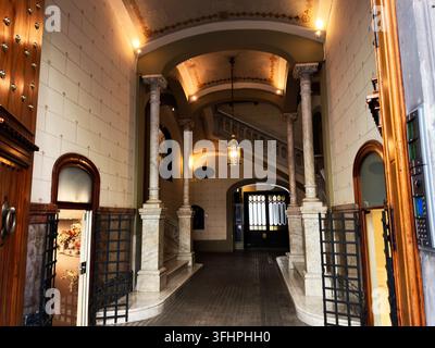 Inneneingang und Treppe mit Marmorsäulen, gewölbter Decke und dekorativem Eisentor. Stockfoto