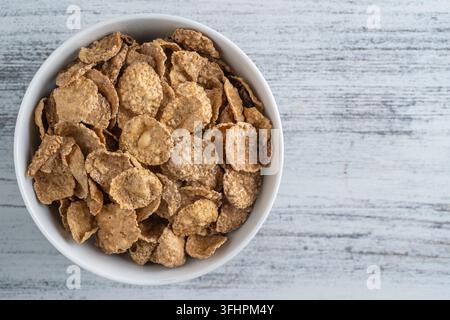 Vollkorn glasierte Flocken in Platte, Nahaufnahme, Draufsicht. Gesundes Frühstück, Vollkornmüsli in einer Schüssel Stockfoto