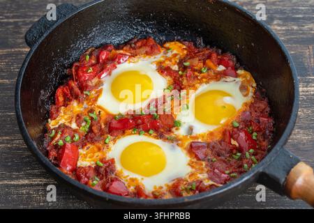 Shakshuka, gebratene Eier mit Tomaten, Zwiebel, rotem Paprika und Gewürzen in der Gusseisenpfanne, Nahaufnahme Stockfoto