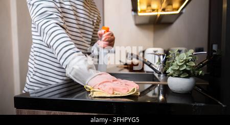 Afroamerikanischer Mann in Gummihandschuhen wischt Staub vom Tisch in der Küche, Hausarbeit, Reinigung, Lifestyle, Haushalt. Stockfoto