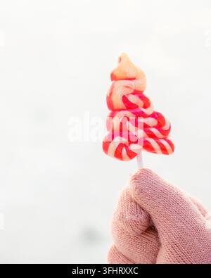 Kleines Kind Hand hält bunte Spiral Lutscher Süßigkeiten auf Stick. Stockfoto