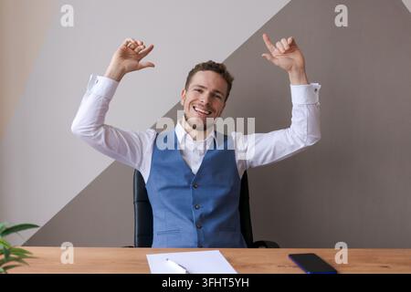 Glücklicher Geschäftsmann mit Bart im Anzug, der lächelnd und aufgeregt mit guten Nachrichten aussieht Stockfoto