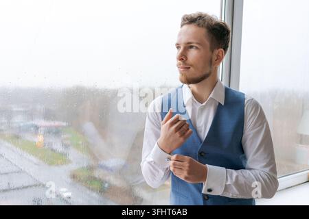 Porträt eines arroganten, scharf gekleideten Mannes in blauem Anzug, der einen Knopf korrigiert Stockfoto