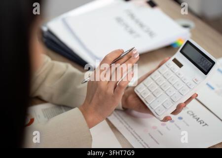 Eine professionelle Frau analysiert Finanzdaten mit einem Taschenrechner und bereitet sich auf eine strategische Besprechung im Büro vor. Stockfoto