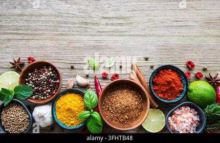Eine Auswahl an verschiedenen bunten Gewürzen auf einem Holztisch in Schalen Stockfoto