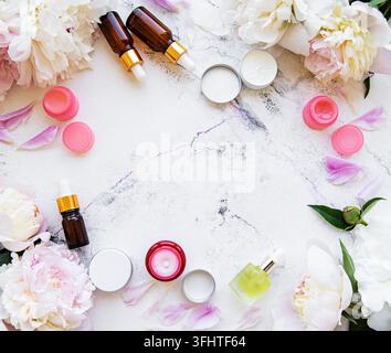 Flache Lage-Komposition mit Pfingstrosen und natürlichen Kosmetikprodukten Stockfoto