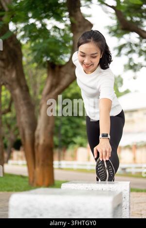 Fitness-Stretching-Routine. Eine junge Frau, die ihre Beine draußen in einem Park ausdehnt. Stockfoto