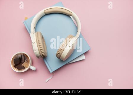 Drahtlose Kopfhörer, die auf Büchern ruhen, mit Kaffee in der Nähe, um Entspannung und Produktivität zu vereinen Stockfoto