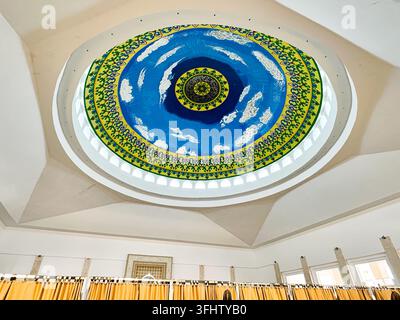 Niedrigwinkelaufnahme einer schön blau bemalten Kuppel mit islamischen Ornamenten und Kalligrafie in einer Moscheegebetsstätte. Stockfoto