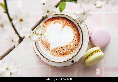 Kaffee mit herzförmigem Muster und süßen Macaron-Desserts Stockfoto