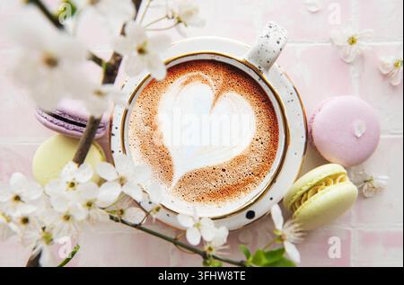 Kaffee mit herzförmigem Muster und süßen Macaron-Desserts Stockfoto