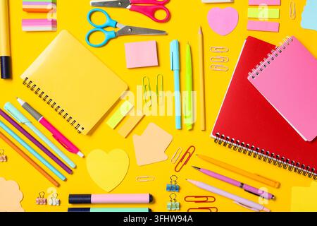 Zurück zur Schule und Bildungsbegriff, farbenfrohe Schreibwaren und Notizbücher, die auf einem hellen gelben Hintergrund für kreative Lernprojekte arrangiert sind Stockfoto