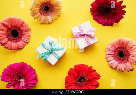 Gerbera-Blumen und Geschenkschachteln auf einem Gelben Stockfoto