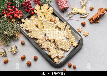 Weihnachtsplätzchen mit Zuckerguss verziert auf einem Backblech mit festlichen Dekorationen Stockfoto