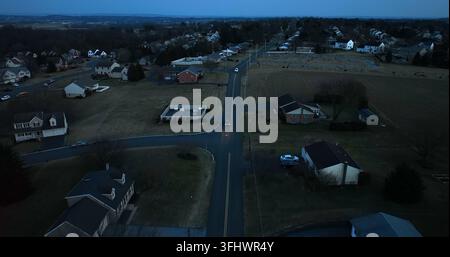 Autos fahren auf der Straße durch ein ländliches amerikanisches Dorf bei Nacht. Luftaufnahme während der Blauen Stunde. Kleinstadt in den USA, Warwick Township, Pennsylvania. Stockfoto