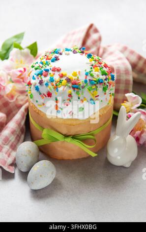 Traditioneller osterkuchen mit bunten Streuseln, begleitet von bemalten Eiern und einer Hasenfigur, die den Geist der ostern verkörpert Stockfoto