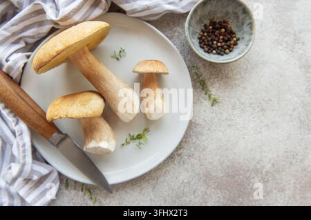 Frische Porcini-Pilze auf einem Teller mit Messer und Pfefferkörnern, bereit zum Kochen Stockfoto