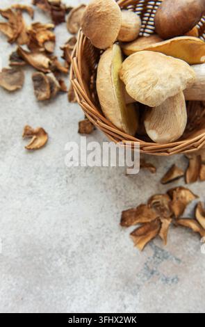 Frische Pilze in einem Korb mit getrockneten Pilzen auf dem Tisch Stockfoto