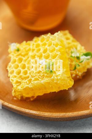 Frischer Honigwaben mit Blume auf Holzplatte und Honig im Glas Stockfoto