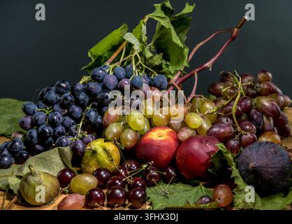 Ein detailliertes Nahaufnahme-Stillleben mit einer Auswahl an frischen Früchten, darunter verschiedene farbige Trauben, reife Pfirsiche, dunkle Feigen und Kirschen, auf einem Stockfoto