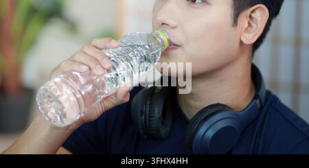 Wellness. Ein junger Mann genießt Trinkwasser, während er Wasser aus einer Flasche trinkt. Stockfoto