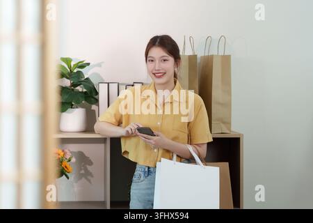 Shopping und digitale Interaktion. Junge Frau, die nach dem Einkaufen ein Smartphone benutzt. Stockfoto