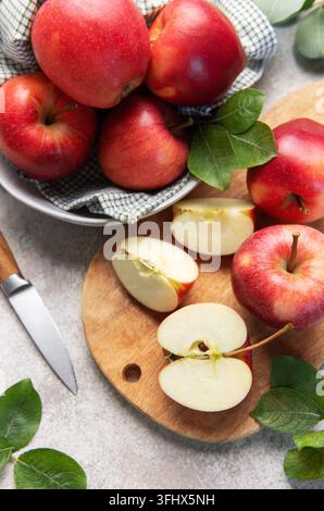 Rote Äpfel, ganz und in Scheiben geschnitten, auf einem Schneidebrett Stockfoto