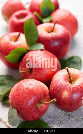 Reife rote Äpfel mit grünen Blättern und Wassertröpfchen schaffen ein frisches und gesundes Bild Stockfoto