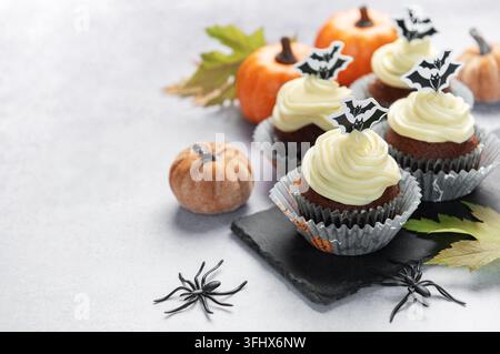 Halloween-Cupcakes mit Fledermaus-Toppern und Kürbischmuck Stockfoto