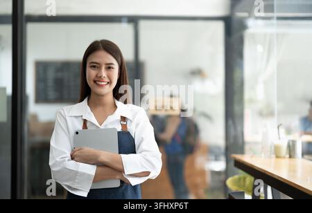Asiatische Barista lächelt bei der Arbeit als kleine Geschäftsinhaberin, Essen und Getränke Café Konzept. Stockfoto
