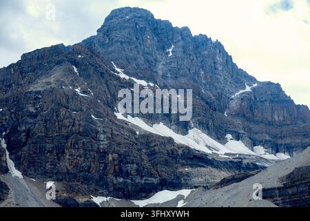 Eine weitläufige, schroffe Bergkette präsentiert ihre imposante Felswand, die mit zurückbleibenden Schneefeldern übersät ist, Jasper, Banff, Alberta, Kanada Stockfoto