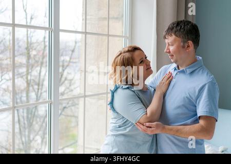 Gemeinsame glückliche Zeit. Lächelndes schönes kaukasisches Ehepaar in Liebe, das sich umarmt Stockfoto