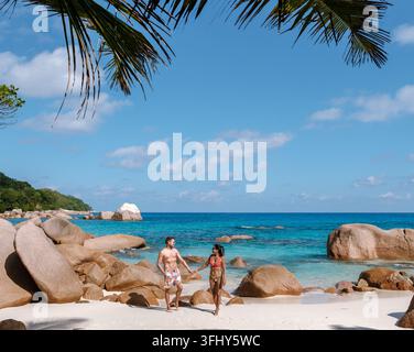 Eine romantische Szene entfaltet sich, während ein Paar Hand in Hand auf dem weichen weißen Sand von Anse Georgette geht. Praslin, Seychellen Stockfoto
