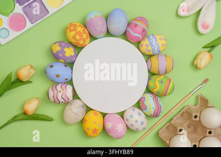 Leuchtende Ostereier in verschiedenen Farben und Mustern umgeben einen leeren Kreis vor grünem Hintergrund, perfekt für festliche Designs. Stockfoto