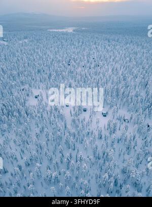 Erleben Sie die unberührte Schönheit von Akaslompolo in Lappland, Finnland, mit gemütlichen Hütten, eingebettet zwischen einer riesigen Weite von schneebedeckten Bäumen unter a s Stockfoto