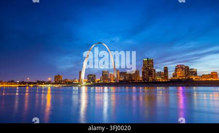 Der ikonische Gateway Arch und die beleuchtete Skyline von St. Louis spiegeln sich im Mississippi während der Blauen Stunde in Missouri wider. Stockfoto
