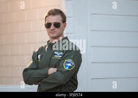 Selbstbewusster männlicher Pilot in grünem Fluganzug mit Fliegerbrille, mit verschränkten Armen im Freien stehend Stockfoto