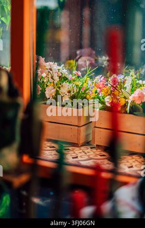 Bezaubernde Schaufensterauslage mit bunten Blumen in Holzkisten Stockfoto