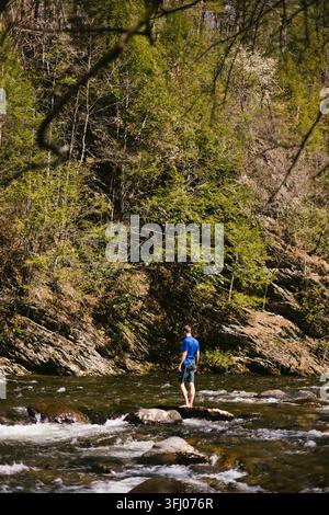 Mann steht barfuß auf einem Felsen in einem Fluss Stockfoto