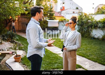 Erwachsenes Paar unterhält sich im Garten während einer Gartenparty Stockfoto