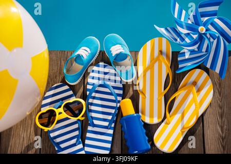 Strand-Flip-Flops und Sonnenbrillen auf Holzplanken in der Nähe des Schwimmbeckens Stockfoto
