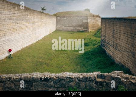 Eine Hochwinkel-Außenaufnahme, die einen historischen Festungskomplex mit dicken, hellen Steinmauern und einem Erdwall zeigt Stockfoto
