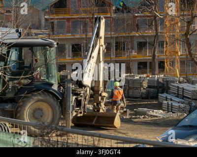 Szklarska Poręba, Polen – 18. Dezember 2025: Schwere Maschinen, die auf staubigem Boden in der Nähe von Gerüststapeln geparkt sind, symbolisieren industrielle Entwicklung und Stockfoto