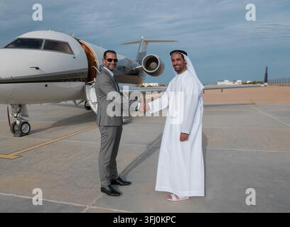 Geschäftspartner aus dem Nahen Osten schütteln vor einem Privatjet auf dem Asphalt die Hand Stockfoto