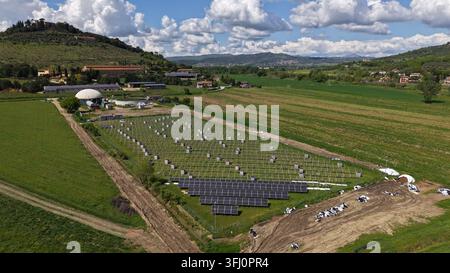 Luftbild einer Solarpaneel-Installation, die sich in einem grünen landwirtschaftlichen Feld befindet, umgeben von sanften Hügeln und ländlicher Landschaft in Monte Melino, Umbr Stockfoto