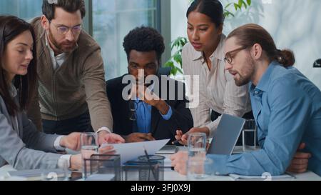 Afroamerikanischer Geschäftsmann, Chef, der einem vielfältigen Geschäftsteam mit multirassischen Mitarbeitern ein Statistikdiagramm vorstellt, glücklich, zufrieden, applaudierend, Daumen hoch zeigend Stockfoto