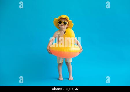 Zufriedenes Kind mit gelbem Gummientchen vor blauem Hintergrund Stockfoto